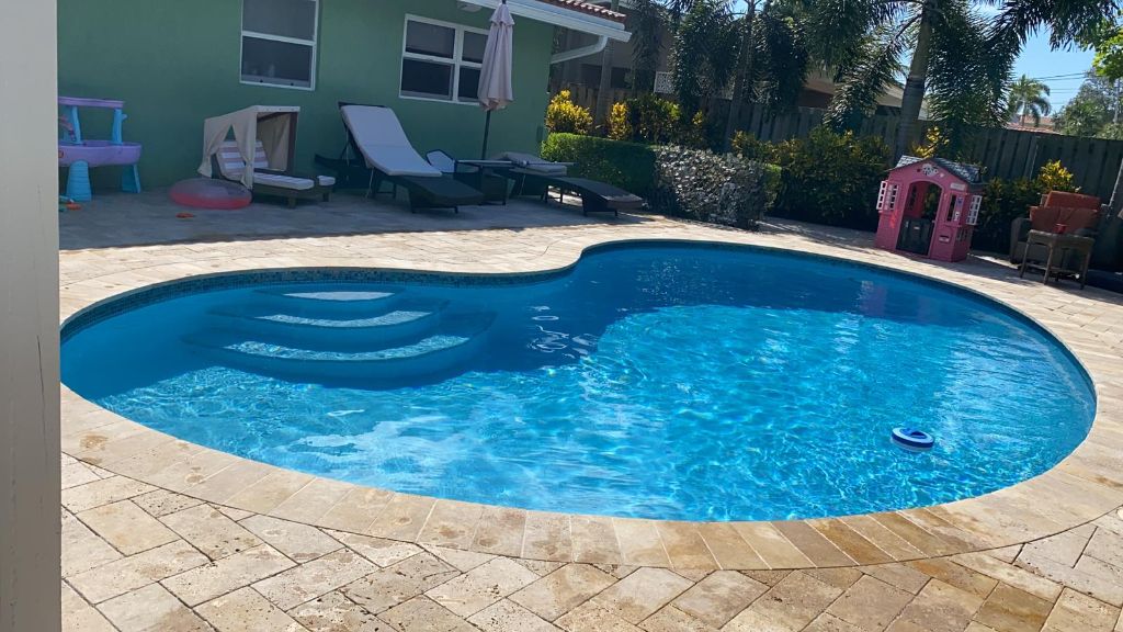 Crystal clear kidney-shaped pool with stone deck