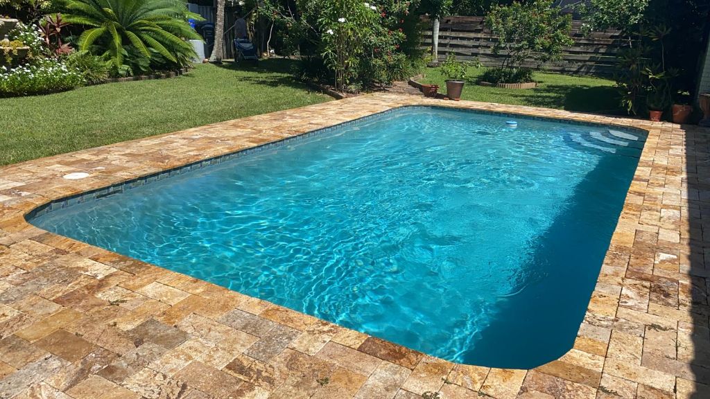 Rectangular pool with stone pavers and garden landscaping