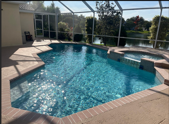 Sparkling luxury pool with spa and lake view under screen enclosure